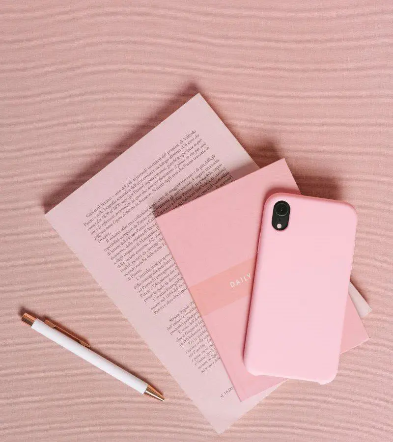new A pink phone case sitting on top of some books.