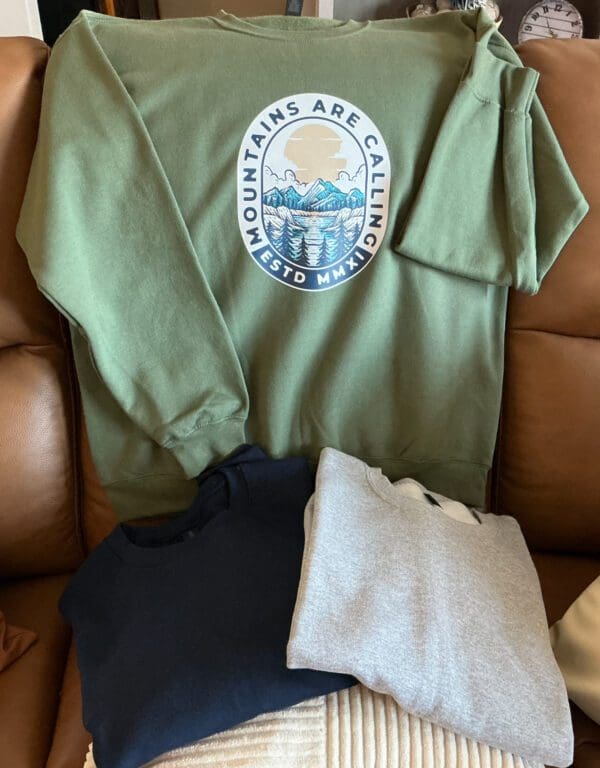 A green sweatshirt sitting on top of a brown couch.