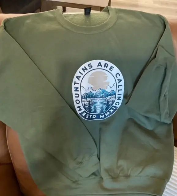 A green sweatshirt with mountains are calling on it.
