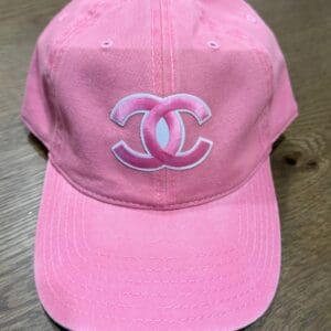 A pink hat with the letters chanel on it.