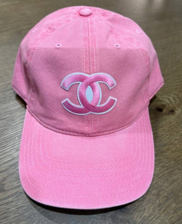 A pink hat with the letters chanel on it.