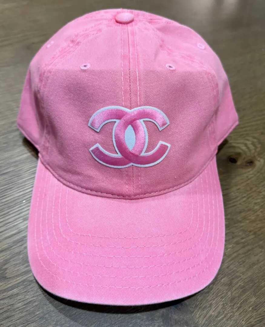 A pink hat with the letters chanel on it.