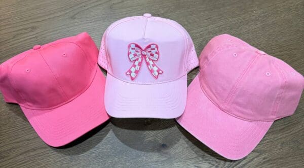 Three pink hats with a bow on each of them.