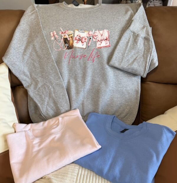 Gray, pink, and blue sweatshirts on couch.