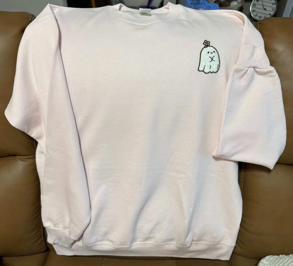 A white sweatshirt with an image of a bottle on it.