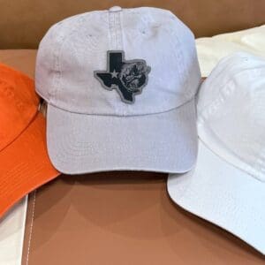 A white hat with an orange cap and a black texas patch.