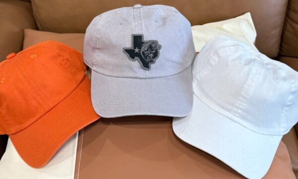 A white hat with an orange cap and a black texas patch.