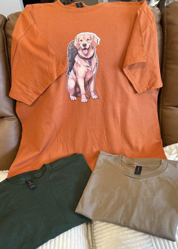 A dog is sitting on top of an orange shirt.
