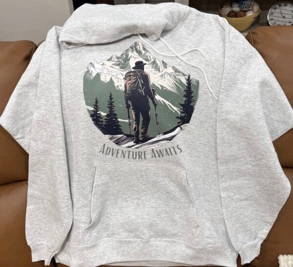 A sweatshirt with an image of a man on top of a mountain.