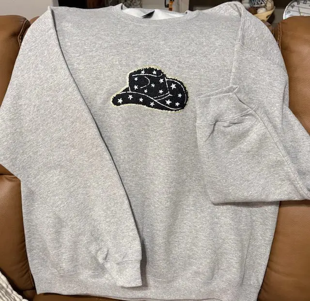 A sweatshirt with a patch of a hat on it.