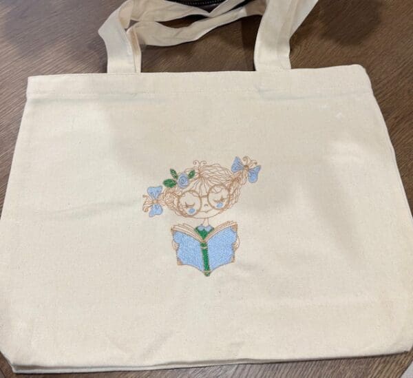 Tote bag with embroidered reading design.