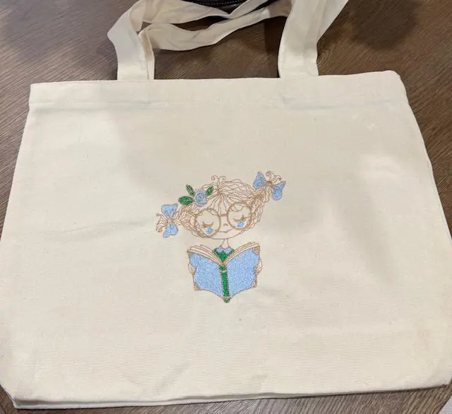 Tote bag with embroidered reading design.