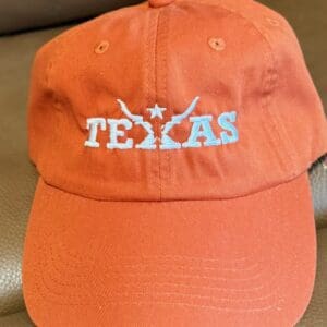 Orange Texas cap with embroidered design.