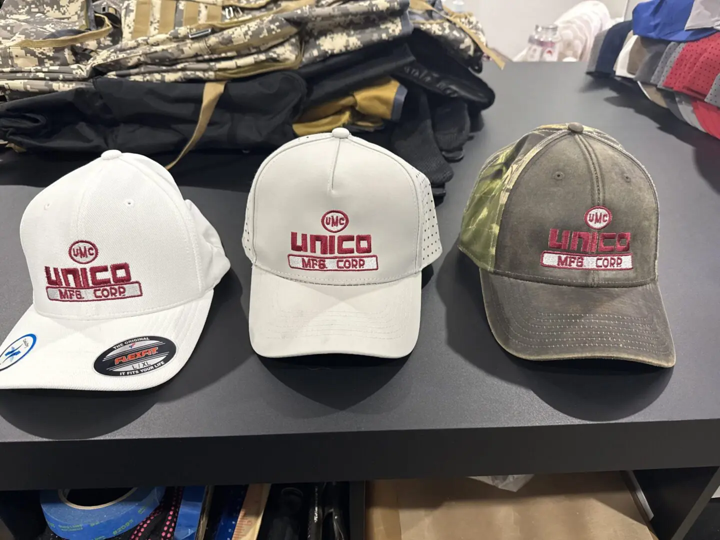 UNICO MFG. CORP Three baseball caps on a table.