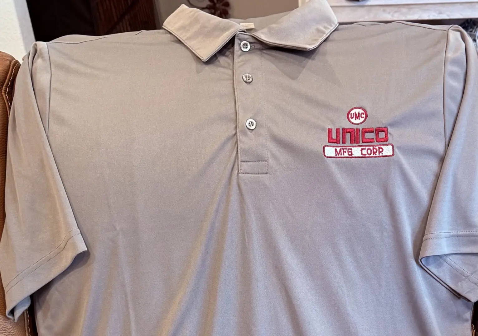 UNICO MFG. CORP. POLO Gray polo shirt with Unico MFG Corp logo.