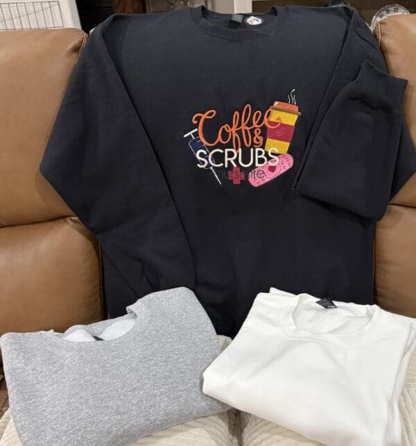 Sweatshirts on couch, one with coffee design.
