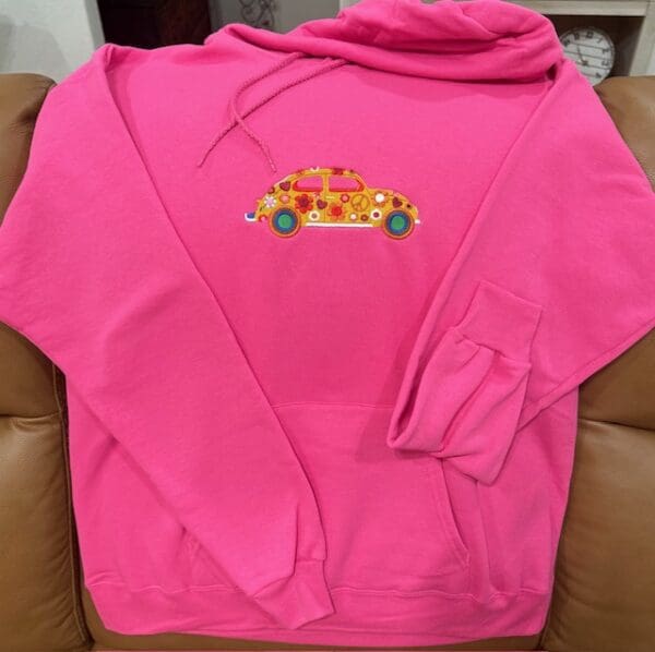 Pink hoodie with colorful car design.