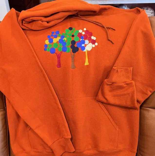 Orange hoodie with colorful tree design.