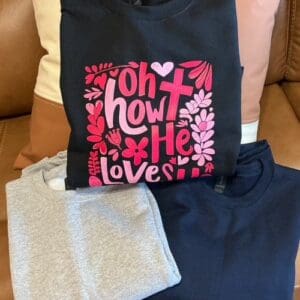 Three folded sweatshirts on a sofa.