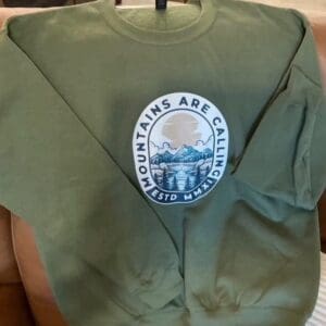 Green sweatshirt with "Mountains Are Calling" design.