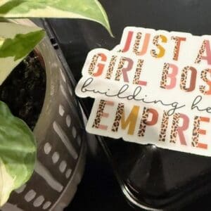 Sticker saying "Just a Girl Boss" near plant.
