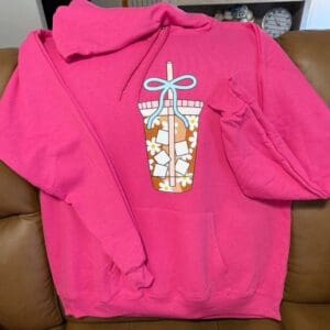 Pink hoodie with floral drink illustration.