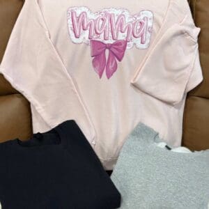 Pink "Mama" sweatshirt with two other shirts.
