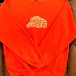 Orange sweatshirt with starry cowboy hat design.