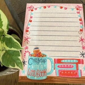 Decorative notepad with plant beside it.