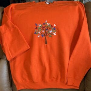 Orange sweatshirt with embroidered colorful tree design.