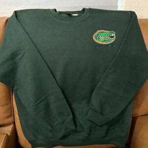 Green sweatshirt with alligator logo on couch.
