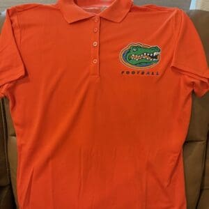Orange polo shirt with alligator football logo.