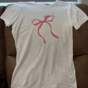 White shirt with pink bow design.