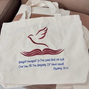 Tote bag with embroidered Bible verse design.