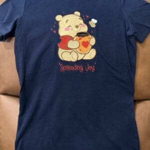 Blue shirt with bear and "Spreading Joy" design.
