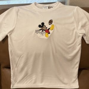 White t-shirt with cartoon character playing football.