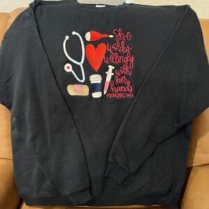 Black sweater with medical-themed embroidery design.