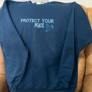 Blue sweatshirt with "Protect Your Peace" text.