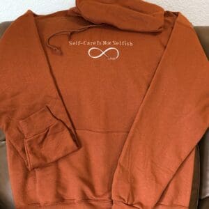 Rust hoodie with self-care message and symbol.